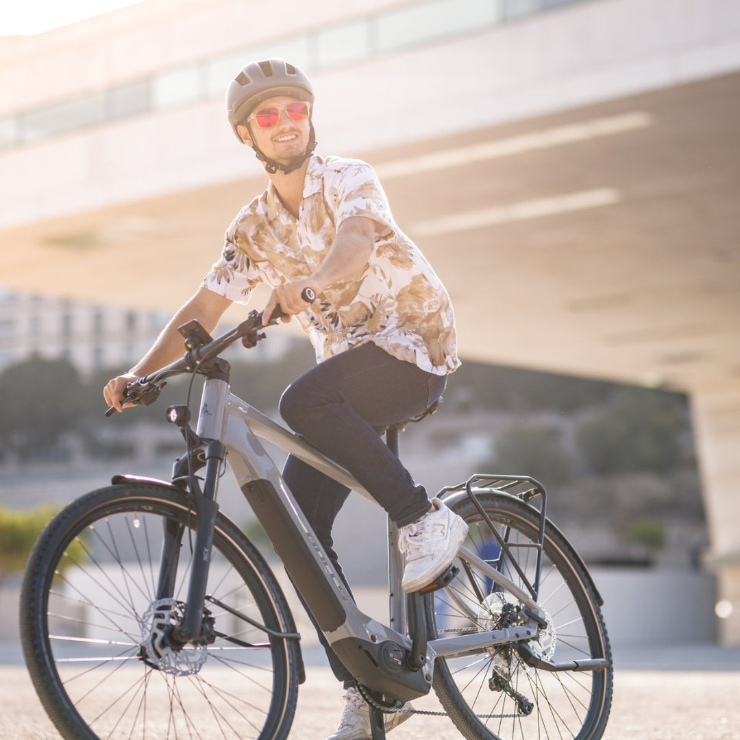 Mann fährt auf E City Bike durch die Stadt.